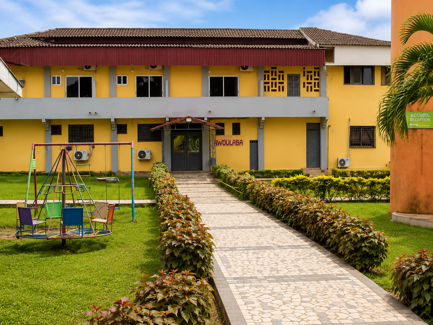 Façade de l'Auberge Akwaba avec jardin et aire de jeux